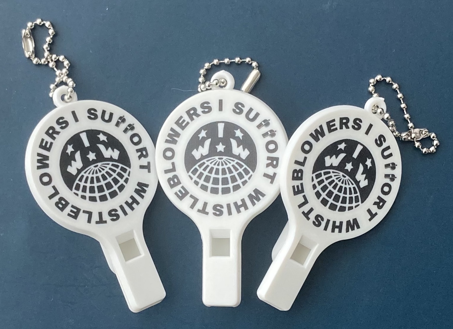 Image shows three whistles. On each is the IWW logo and around it, it says "I support whistleblowers"